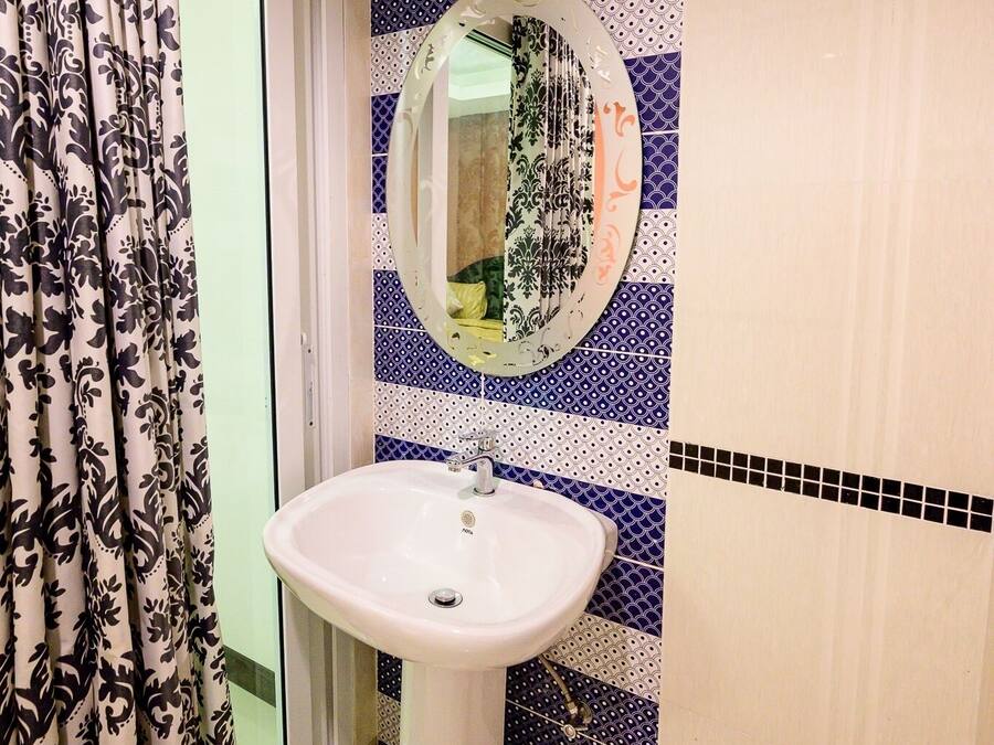 Un baño con un lavabo blanco, un espejo y baldosas estampadas.