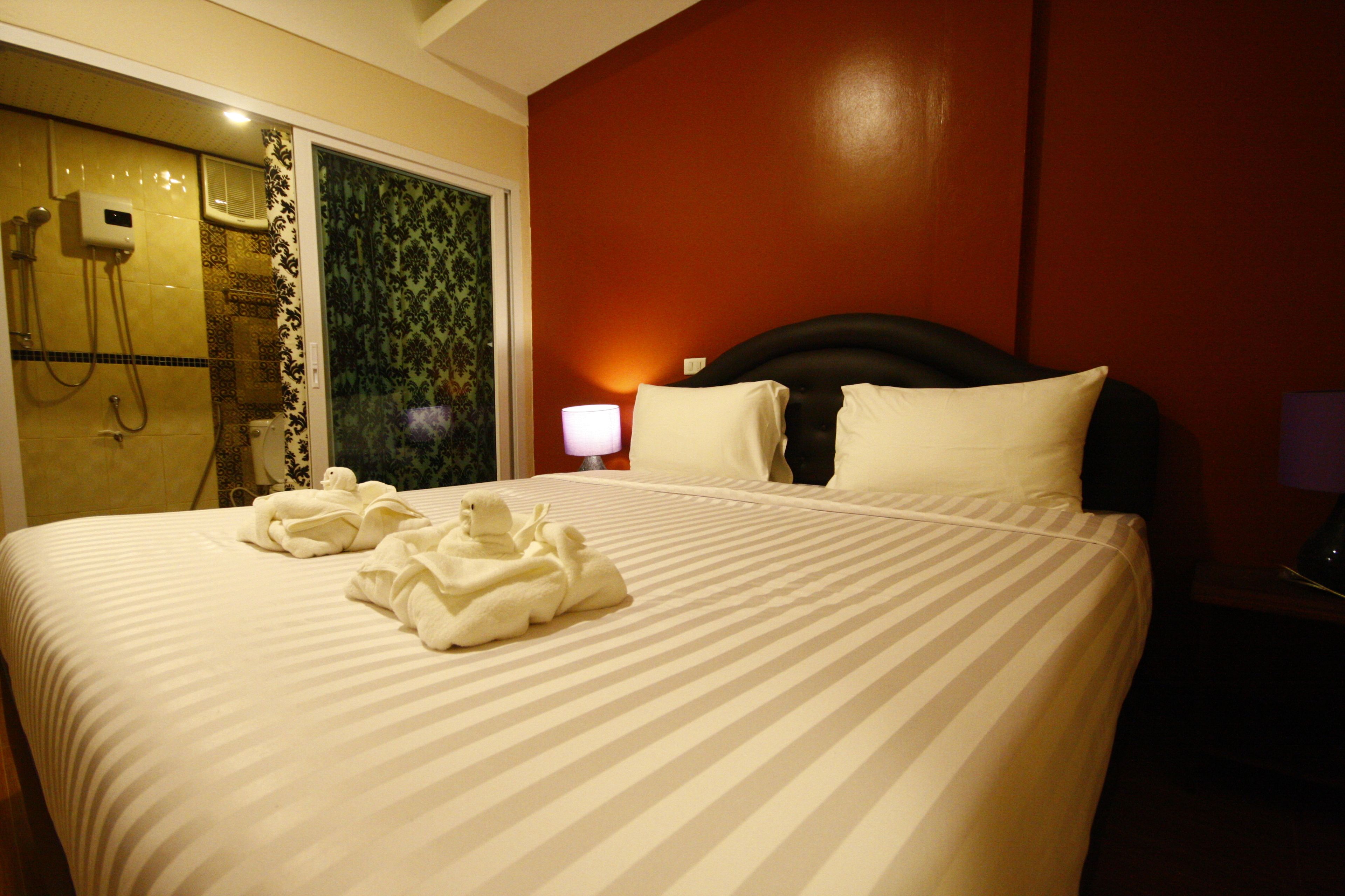 A hotel room with a large bed, a shower area, and a nightstand with a lamp.