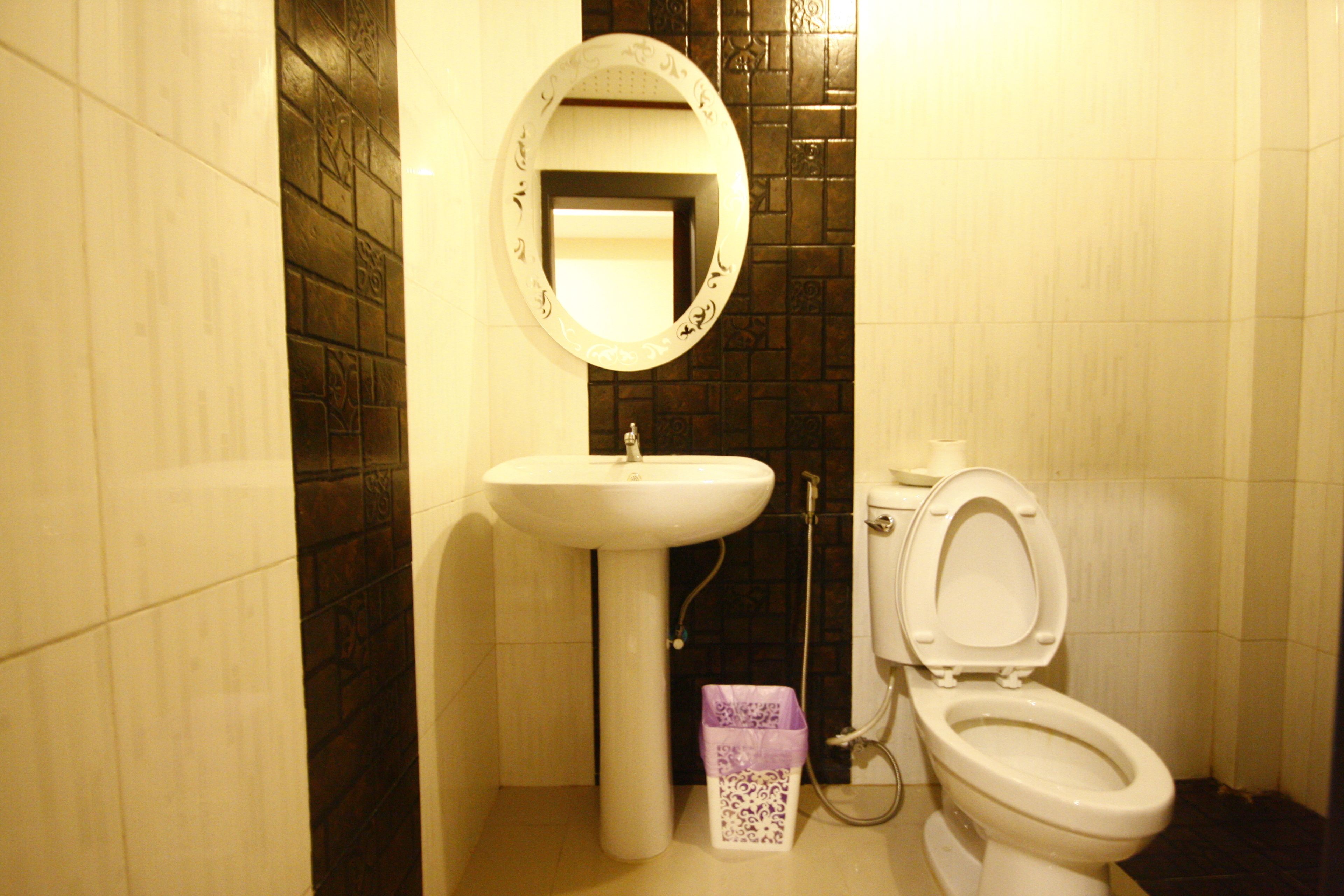 Een badkamer met een wit wastafel, toilet en spiegel.