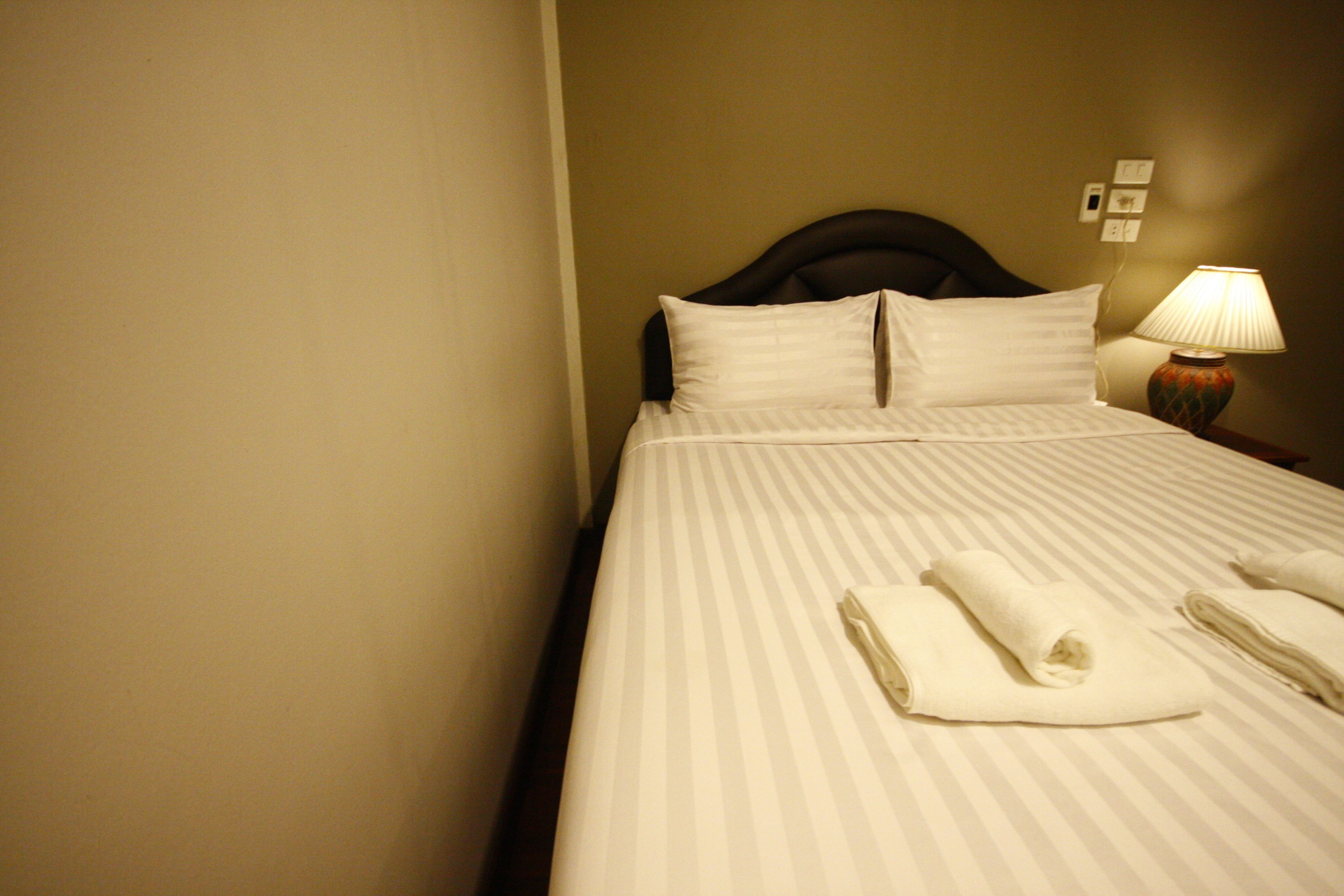 A neatly made bed with striped bedding and two folded towels on the bed.