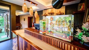 A reception area with a wooden counter, hanging pendant lights, and a decorative glass display case. - Rommai At Home (Prachin Buri)