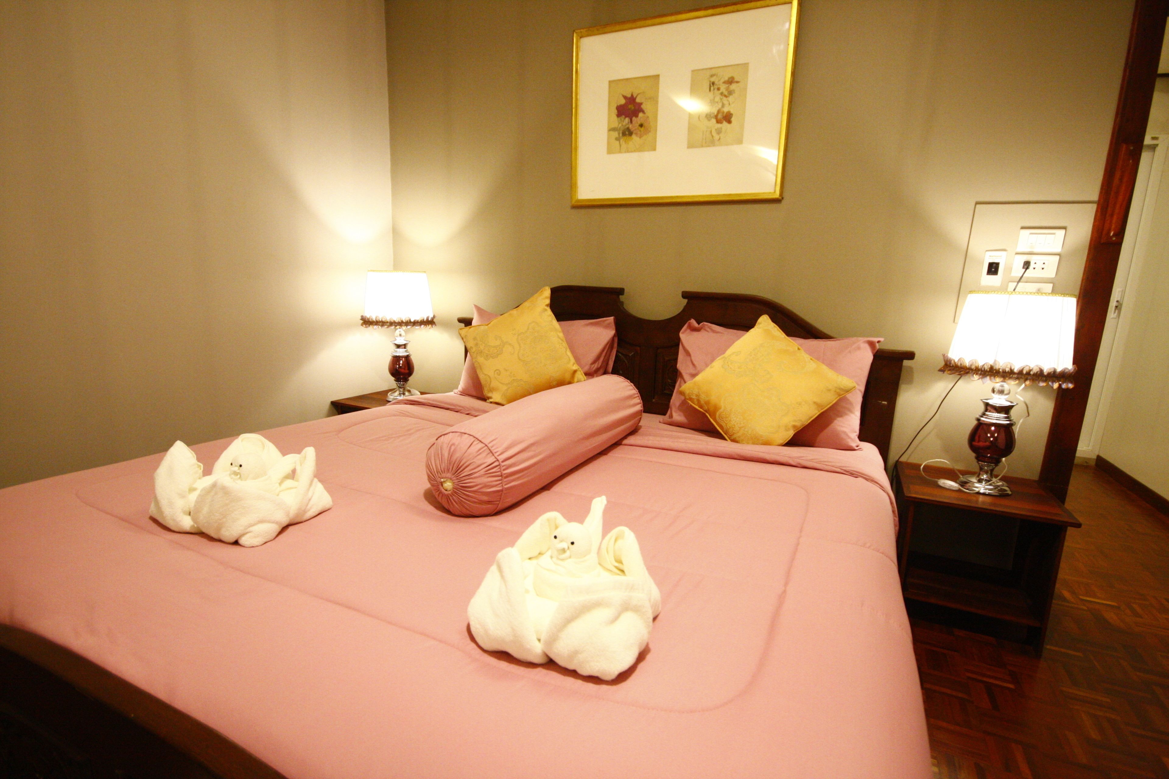 Una habitación de hotel con una cama grande, dos lámparas de noche y un cuadro en la pared.