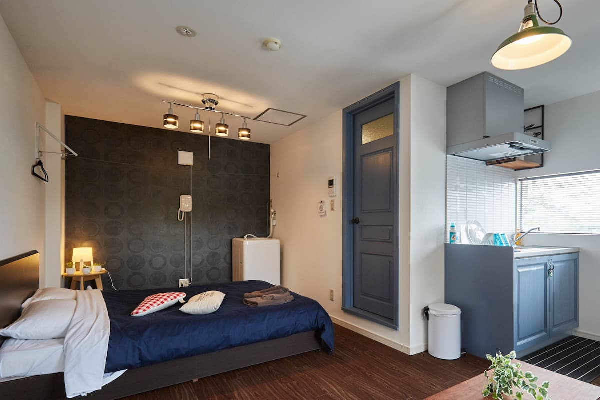 A modern bedroom with a bed, bedside table, and a small table with a plant.