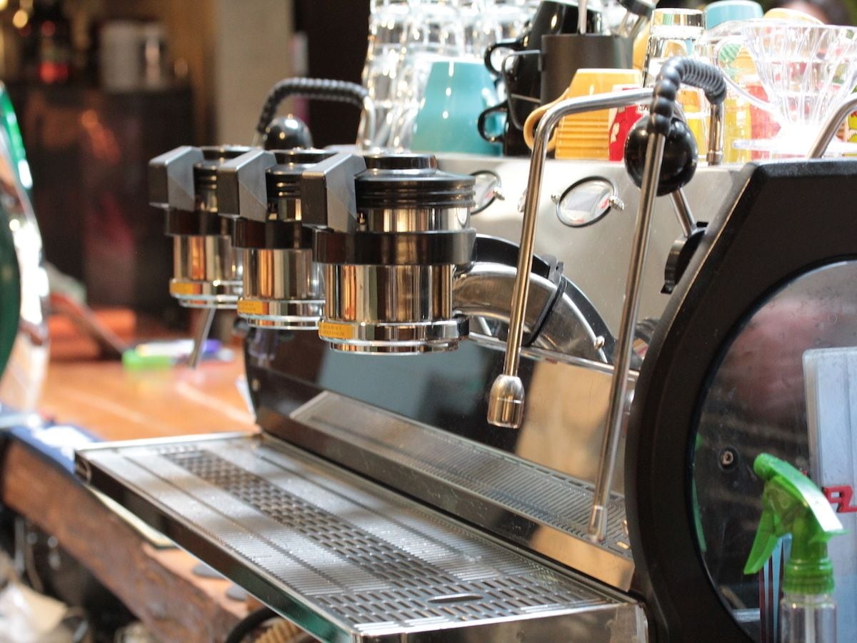 Une machine à café dotée de plusieurs porte-filtres et d’un bac d’égouttement en métal.
