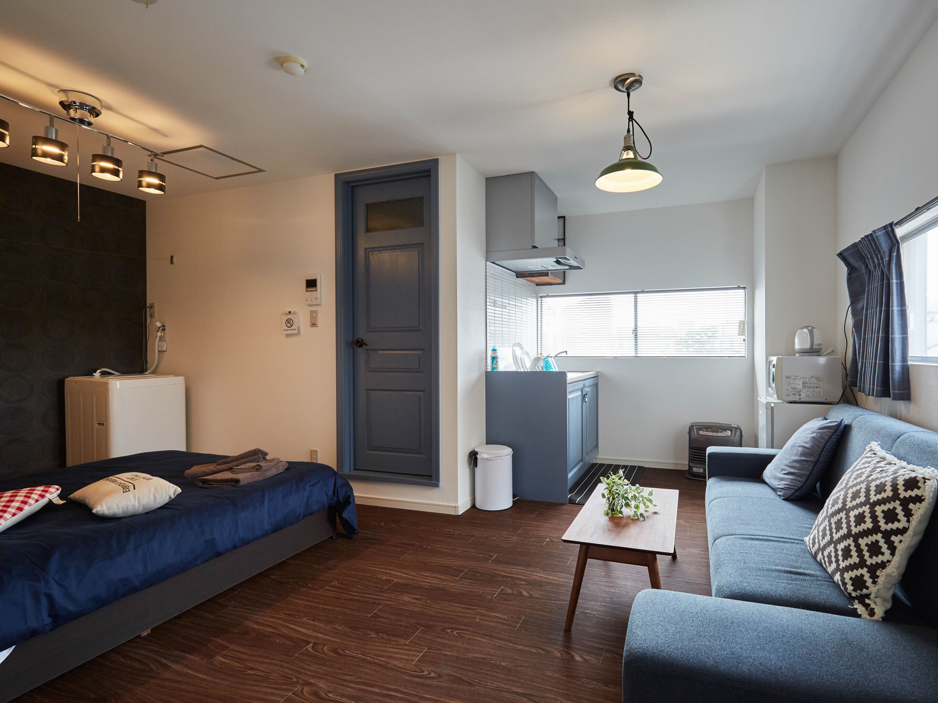 A modern, compact living space with a bed, sofa, and kitchenette.