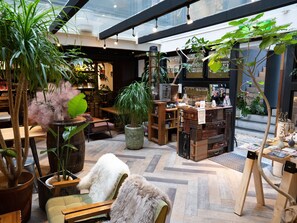 A cozy indoor space with wooden furniture, potted plants, and a variety of items on display. - Hostel & Bar CUORE KURASHIKI (Kurashiki)
