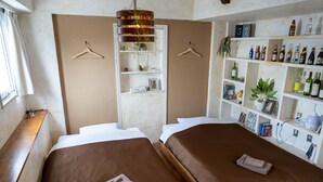 Una camera d'albergo con due letti, una libreria e una finestra con tenda.