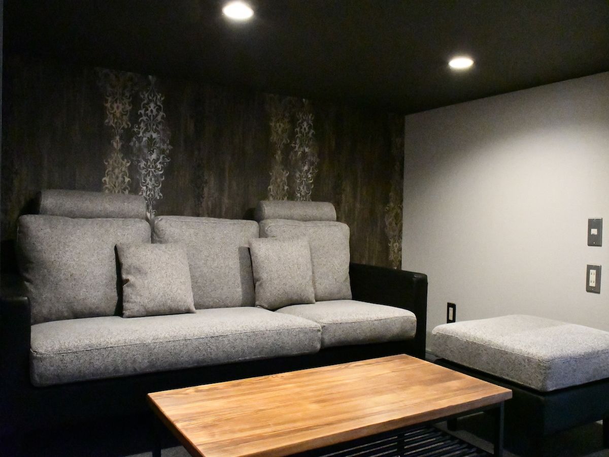 Una sala moderna con un sofá gris, un reposapiés a juego y una mesa de centro de madera.