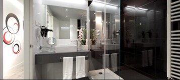 Ein modernes Badezimmer mit Duschkabine aus Glas, einem großen Spiegel und einem weißen Waschbecken.