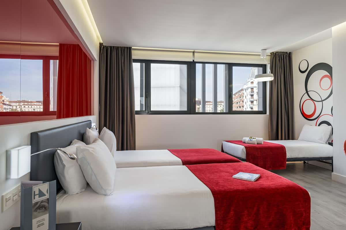 A hotel room with two beds, a large window with curtains, a city view, and a modern design.