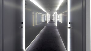 Un pasillo largo y estrecho con puertas a ambos lados, cada una identificada con un número.