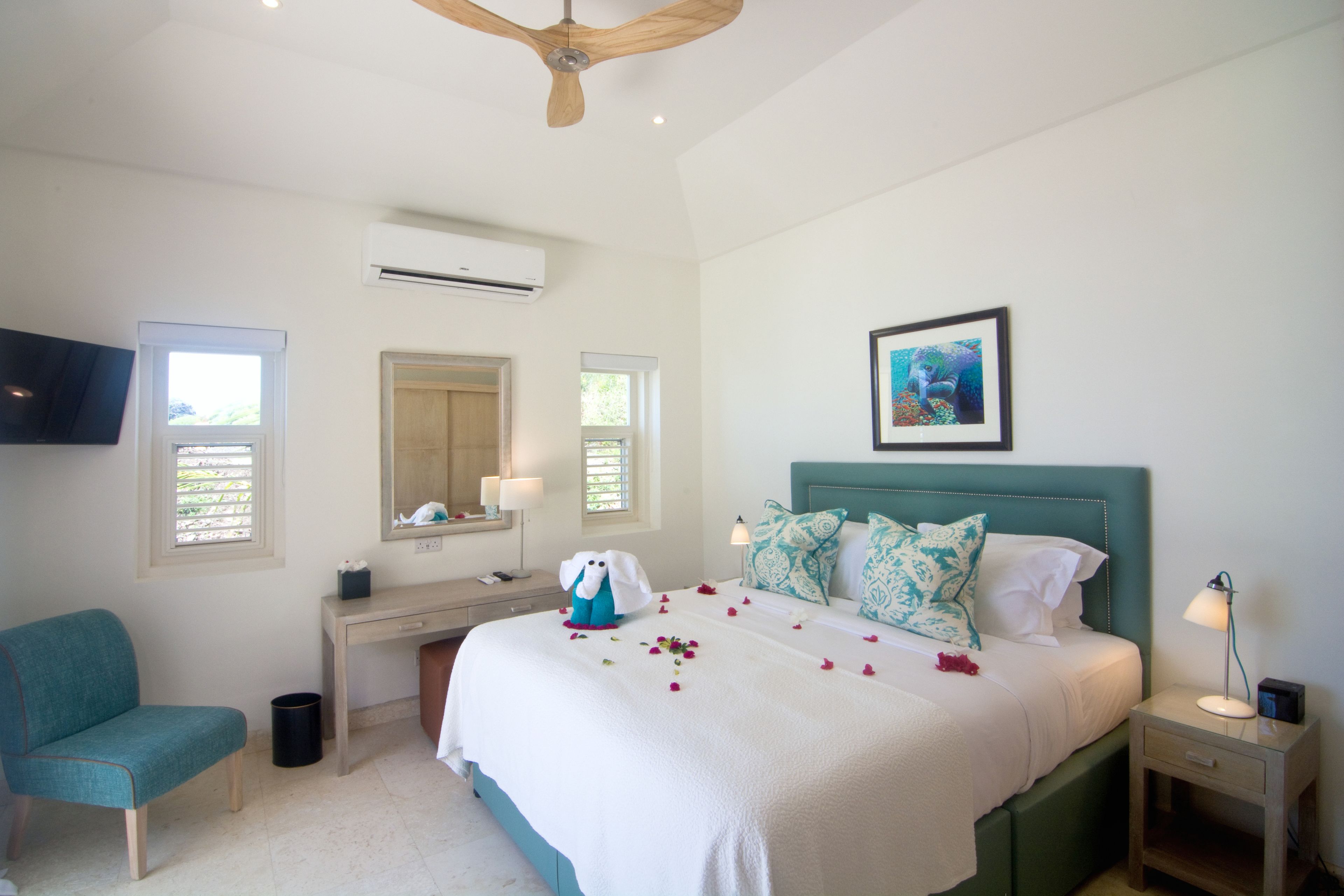 A bedroom with a bed, a desk, a chair, a TV, and an air conditioning unit.