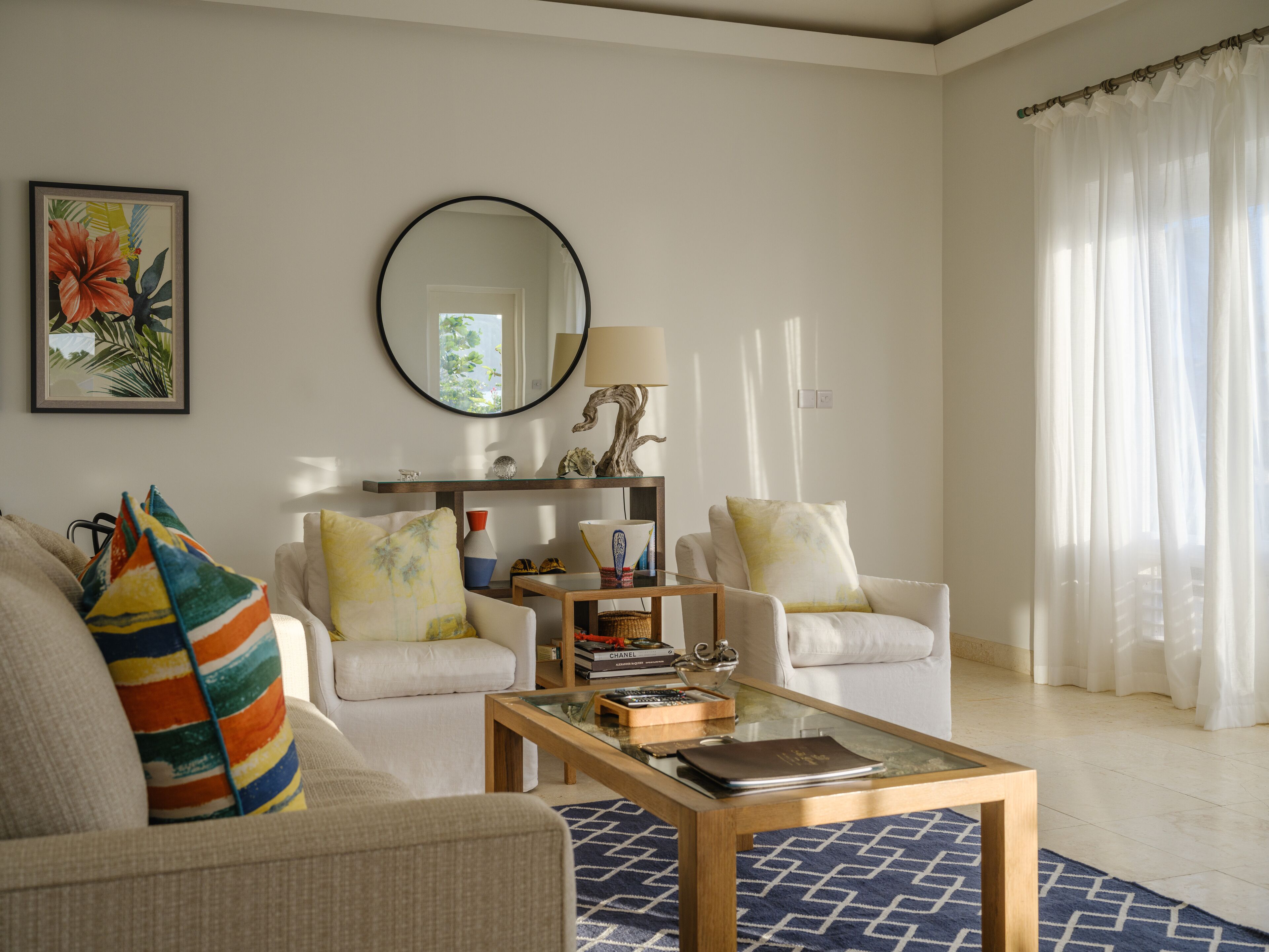 A living room with two white sofas, a coffee table, a mirror, and a framed picture on the wall.