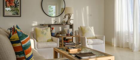 A living room with two white sofas, a coffee table, a mirror, and a framed picture on the wall.