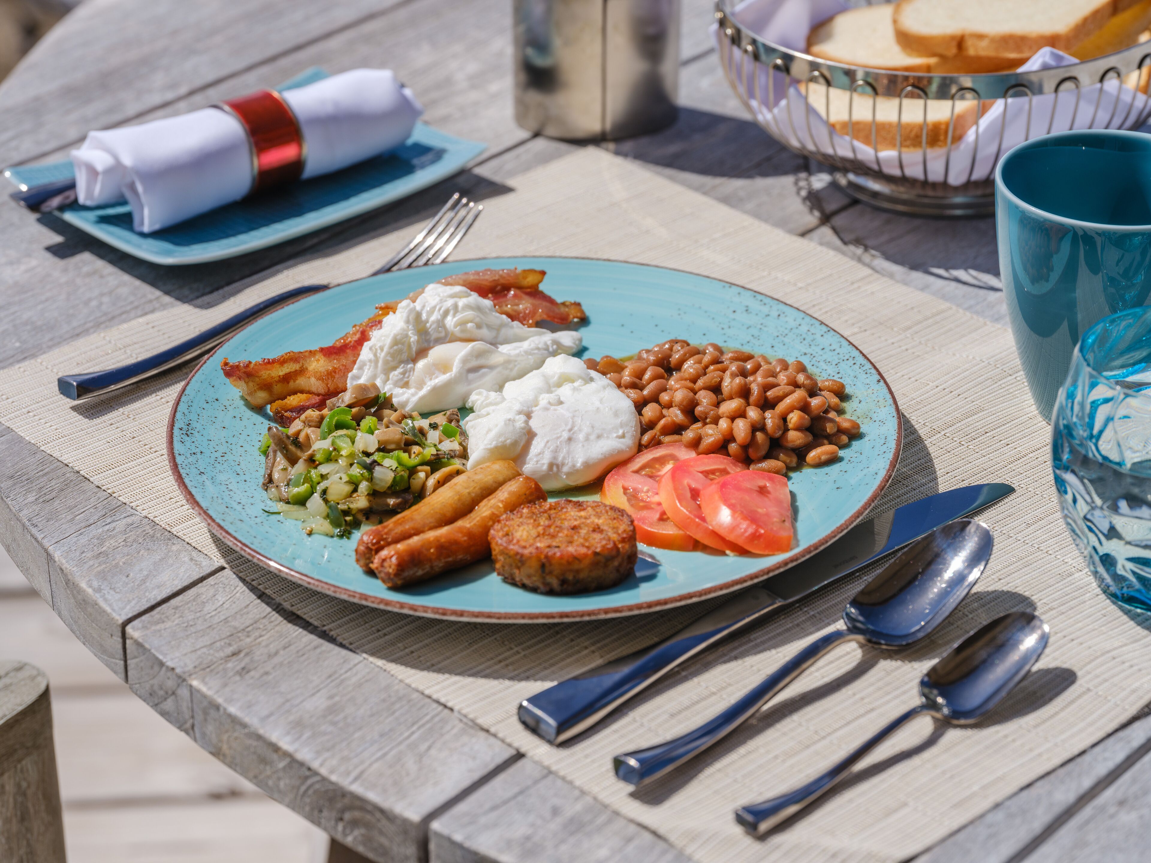 A plate of food with beans, tomatoes, and sausages on a table.