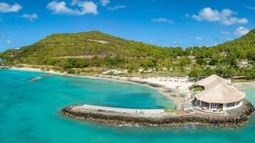 A coastal resort with a thatched-roof building, a sandy beach, and a rocky outcrop.