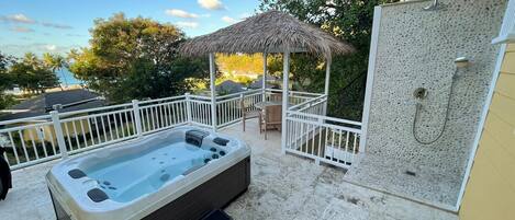 Un jacuzzi y zona de ducha con vistas a la playa y a los árboles.