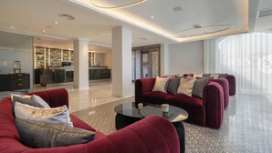 Een ruime lobby met een receptiebalie, een zithoek met banken, en een groot raam dat voor natuurlijk licht zorgt.