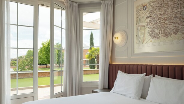 Een hotelkamer met een groot bed, uitzicht op de omgeving en een kaart aan de muur.
