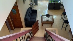 A wooden staircase with pink railings leading to a living area with a sofa and a coffee table. - Star House (Port-au-Prince)
