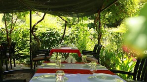 An outdoor dining area with tables set for two, surrounded by lush greenery. - Dolunay Apart Otel (Kemer)