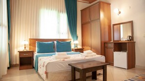 A bedroom with a bed, nightstands, a desk, a dresser, and a refrigerator. - Dolunay Apart Otel (Kemer)
