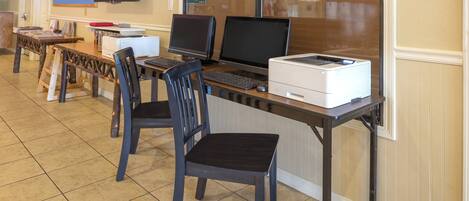 Un laboratorio de computadoras con múltiples estaciones de trabajo, cada una equipada con monitor, teclado e impresora.