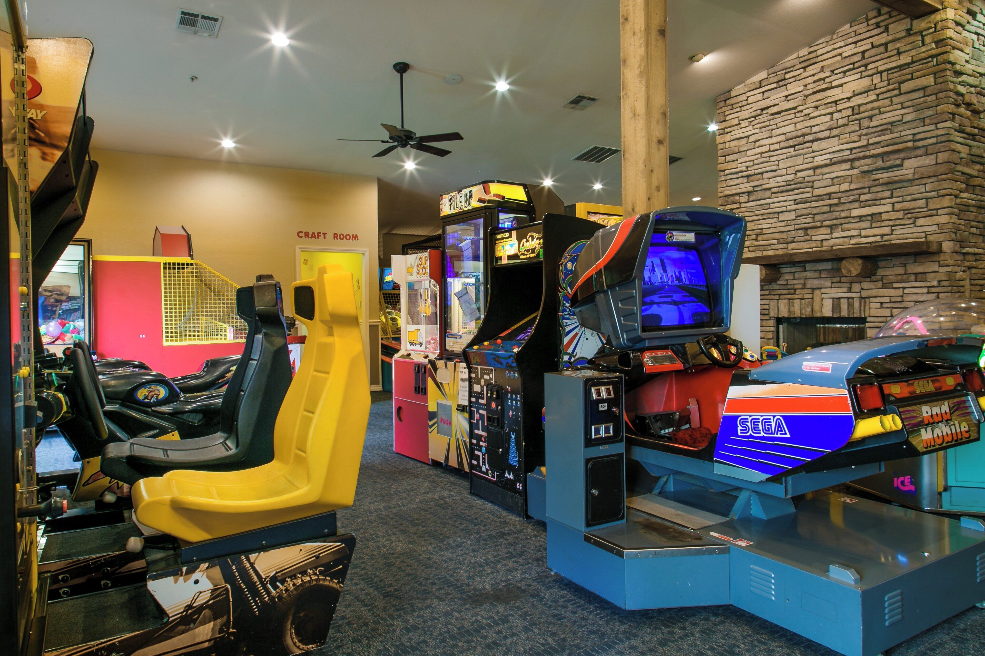 A room with arcade games, a craft room, and a ceiling fan.
