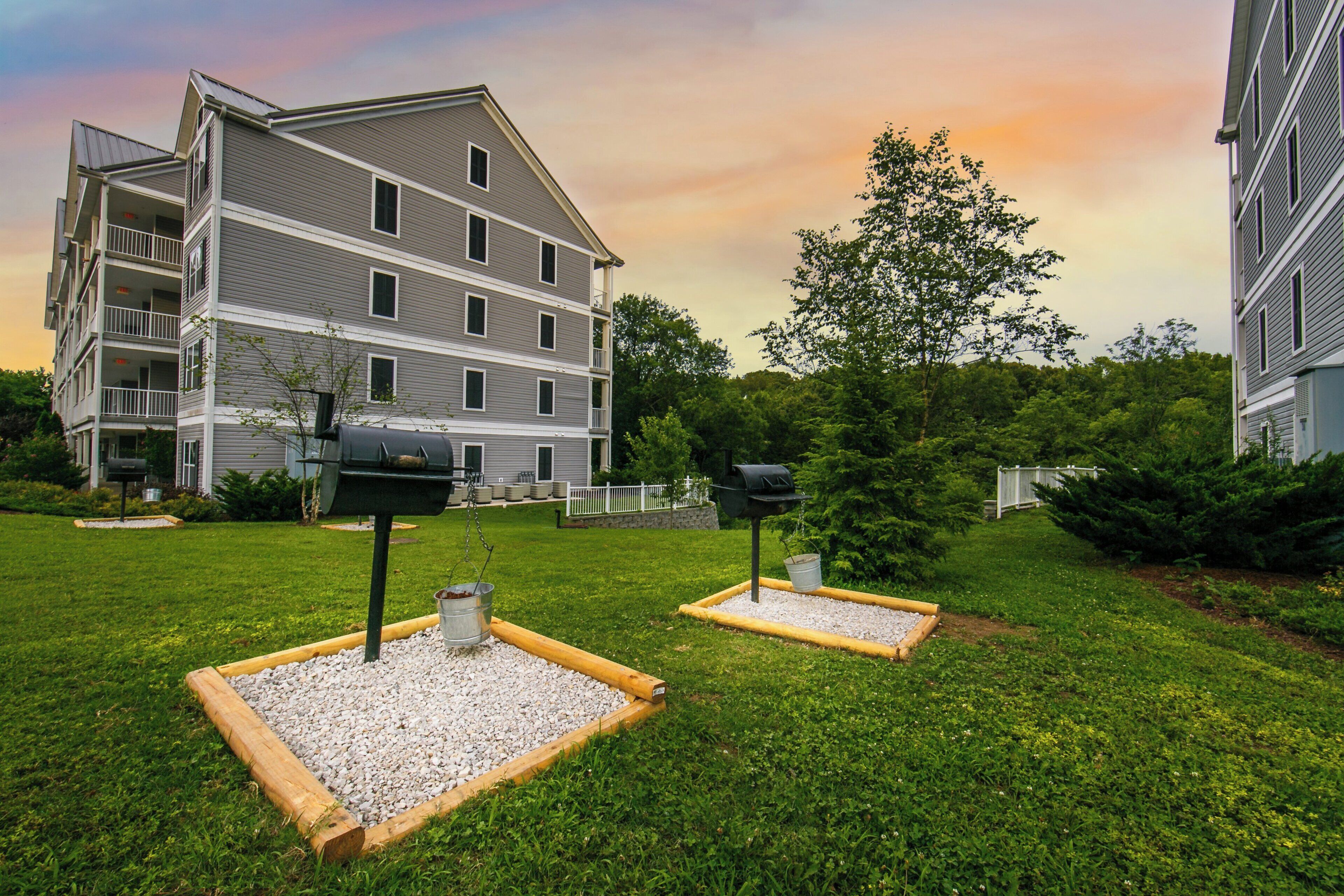 A multi-story residential building with a balcony, a well-maintained lawn, and two outdoor mailboxes.