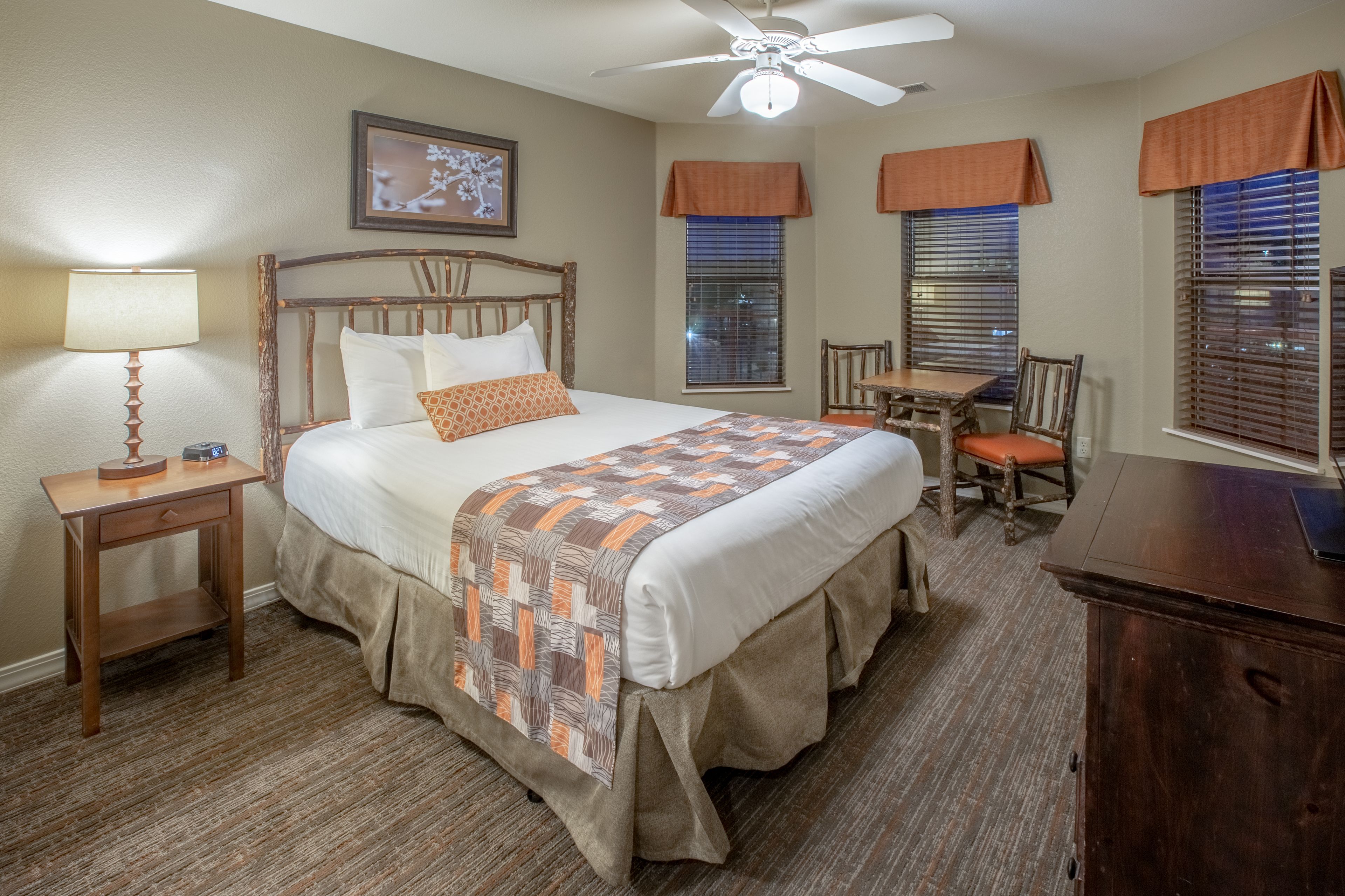A neatly arranged bedroom with a bed, bedside table, chair, and a desk.