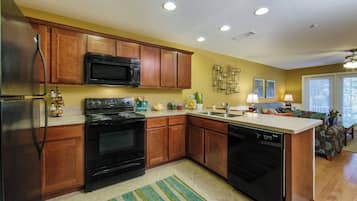 A kitchen with wooden cabinets, a black microwave, a stove, and a dishwasher.