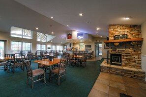 A spacious indoor dining area with multiple tables and chairs, a stone fireplace, and a kitchen area in the background. - Holiday Inn Club Vacations Holiday Hills Resort Branson by IHG (Branson)