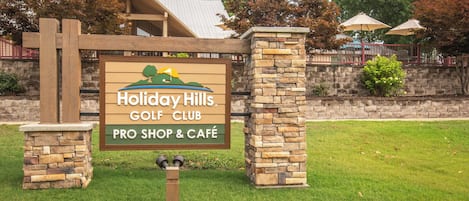 A sign for Holiday Hills Golf Club with a pro shop and cafe.