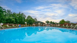 A clear blue swimming pool surrounded by green lounge chairs and a wooden building with a roof. - Holiday Inn Club Vacations Holiday Hills Resort Branson by IHG (Branson)