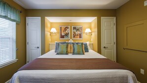 Un dormitorio con una cama grande, dos lámparas de pared y dos cuadros enmarcados sobre la cama.