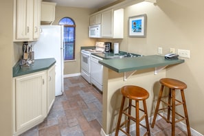 A kitchen with white appliances, a green countertop, and wooden stools. - Holiday Inn Club Vacations Holiday Hills Resort Branson by IHG (Branson)