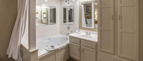 A bathroom with a bathtub, two sinks, and a large mirror.