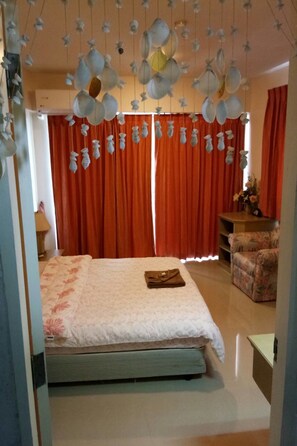 A bedroom with a bed, curtains, a chair, and hanging light fixtures. - Vip Condochain By Kittima (Rayong)