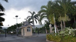 A gated entrance with a small building, palm trees, and a clear sky. - Richmond Estate (St. Ann's Bay)