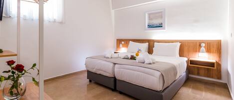 Un dormitorio moderno con una cama grande, cabecera de madera, mesita de noche con lámpara y un jarrón con flores.