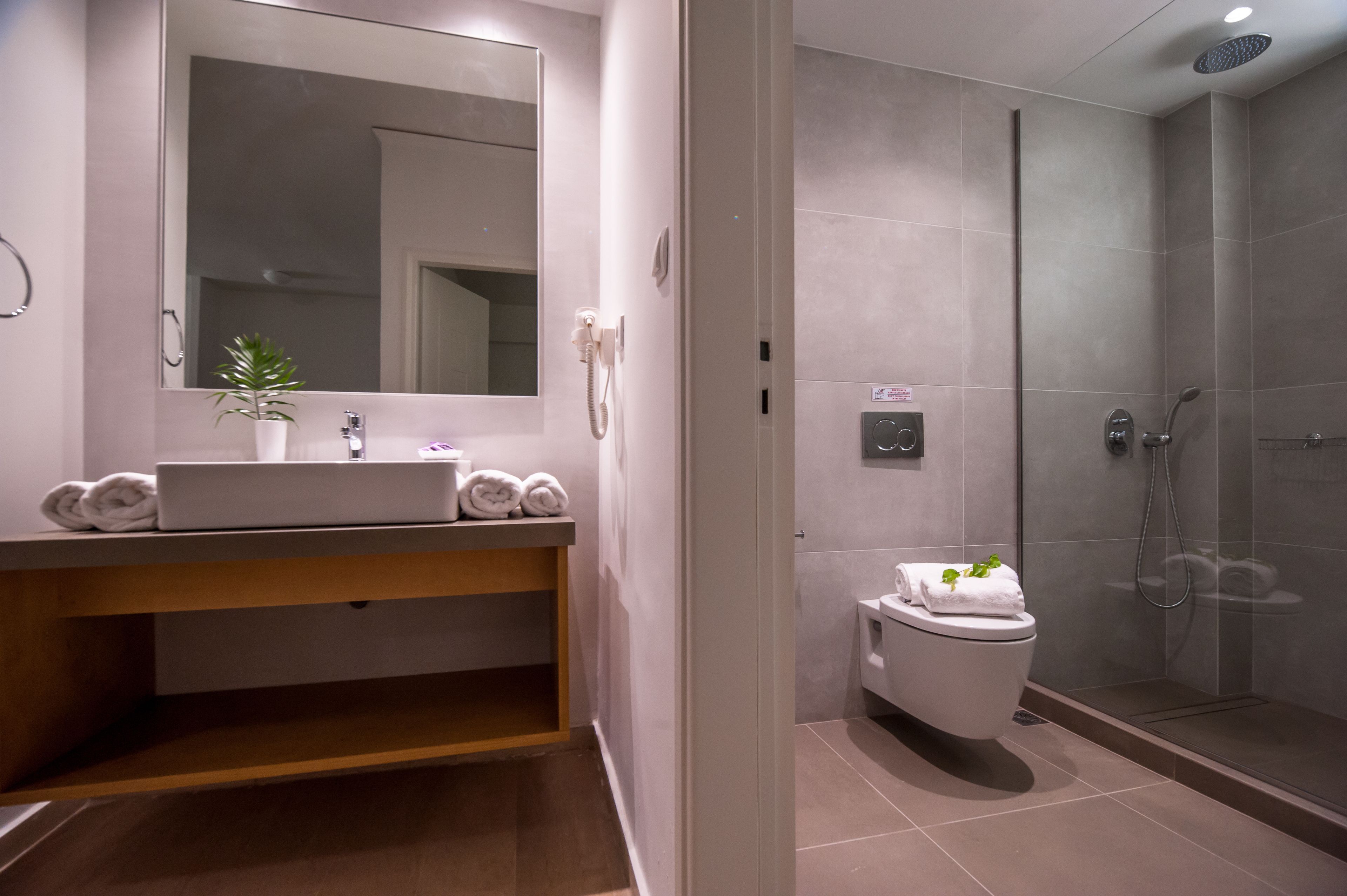 A modern bathroom with a sink, mirror, towel rack, and a shower area.