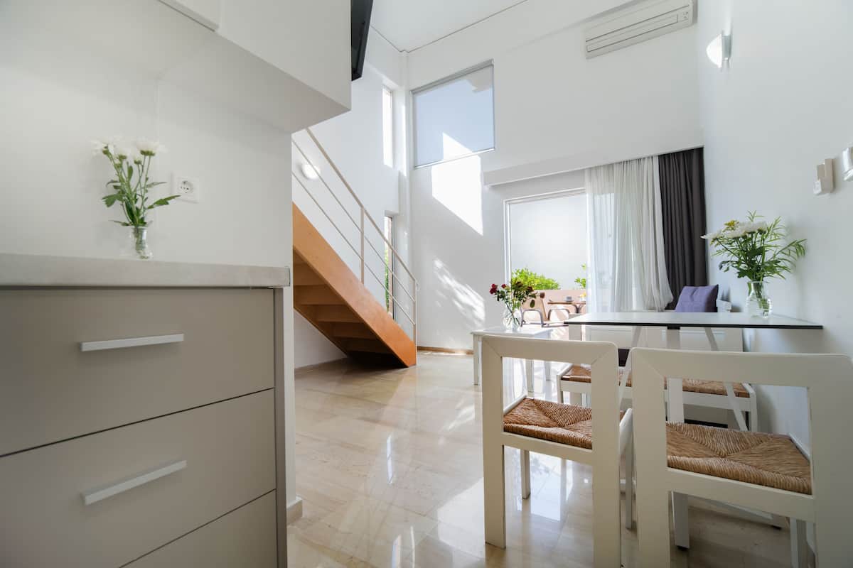 A modern kitchen with white cabinets and a dining area with white chairs and a table.