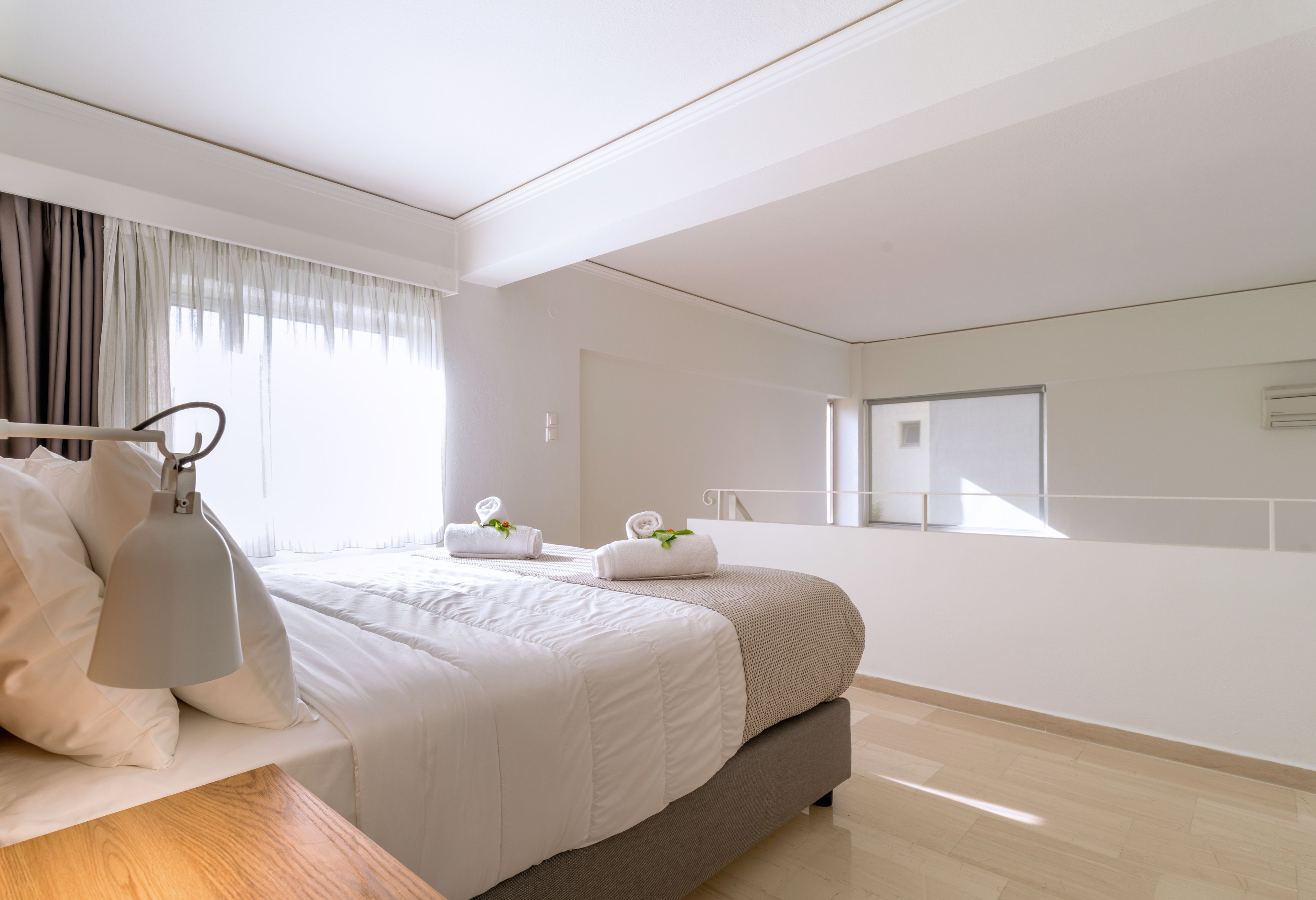 A modern hotel room with a large bed, a wooden nightstand, a desk, and a large mirror.