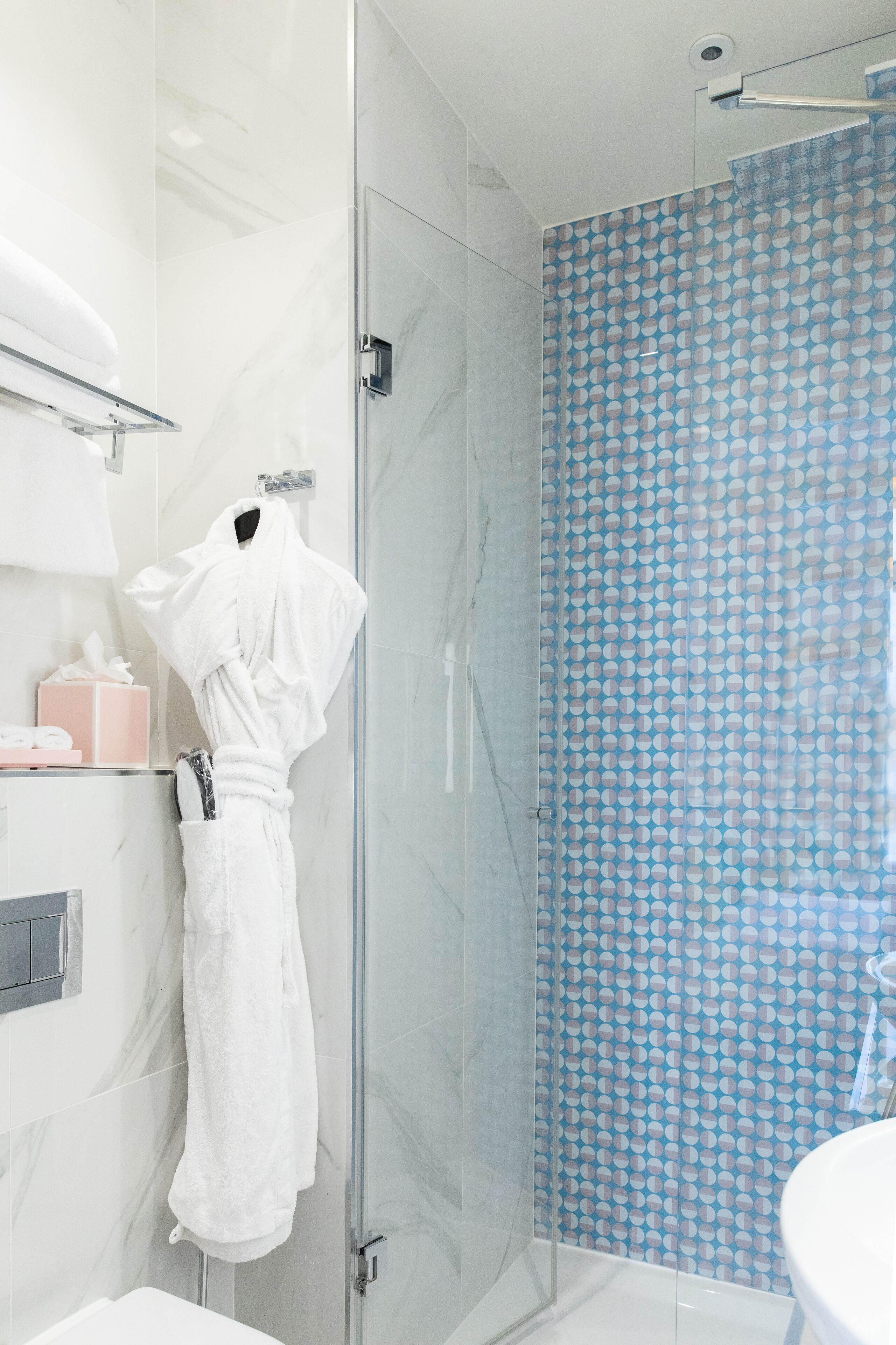 Un baño moderno con cabina de ducha de vidrio, una bañera blanca y un lavamanos.
