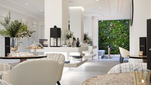 A modern interior with a central bar area, seating, and a green wall. - Hôtel Dress Code (Paris)