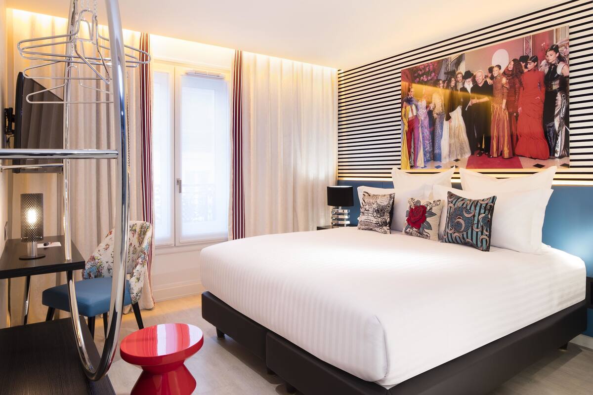 Una habitació d'hotel moderna amb un llit gran, una taula de treball i una cadira.