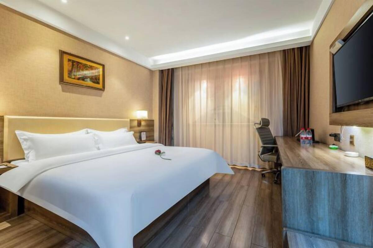 Une chambre d’hôtel avec un grand lit, un bureau avec une chaise, une télévision et un tableau au mur.