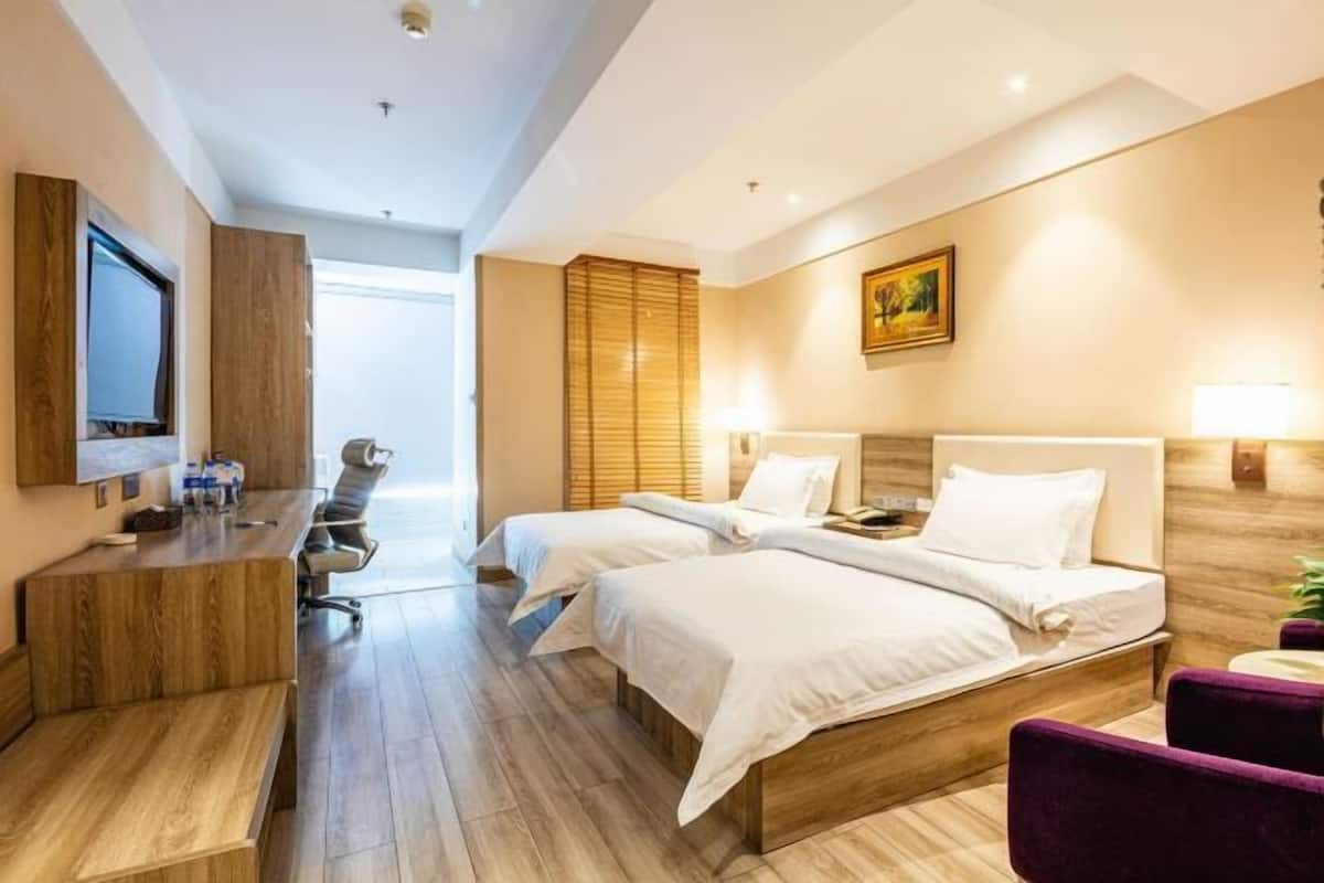 Une chambre d’hôtel avec deux lits, un bureau, une chaise et un téléviseur.