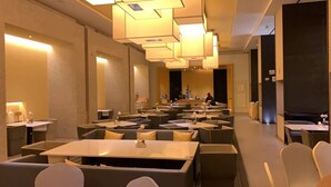 Un espace de restauration moderne, doté de plusieurs tables et chaises, d’une scène centrale et d’une personne debout sur la scène.