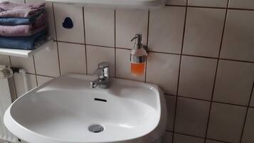 A bathroom with a white sink, a mirror above it, and a towel rack with folded towels.